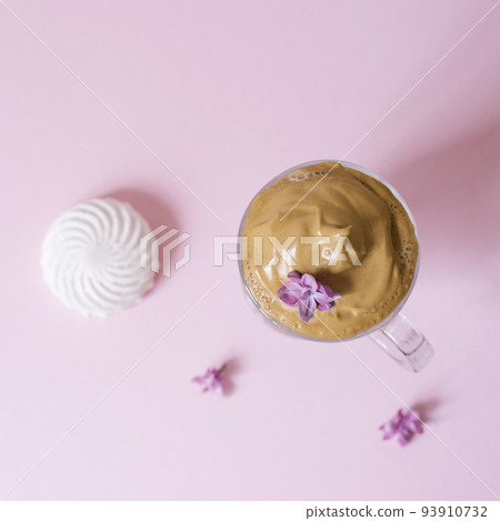 Beautiful dalgon coffee drink. Coffee mug with foam and lilac flower on a lilac pink background. Top view Beautiful dalgon coffee drink. Coffee mug with foam and lilac flower on a lilac pink background. Top view 93910732