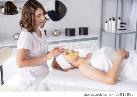 A cosmetologist in the office does a facial massage to a girl A cosmetologist in the office does a facial massage to a girl 93913993