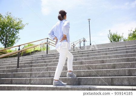 A middle-aged woman who feels pain in her lower back while walking 93914185