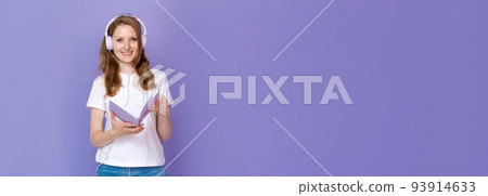 Charming student girl listening to music through headphones holds an open 93914633