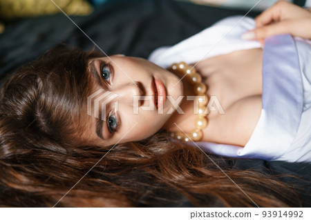 Beautiful seductive young brunette woman with big beads in a white blouse 93914992