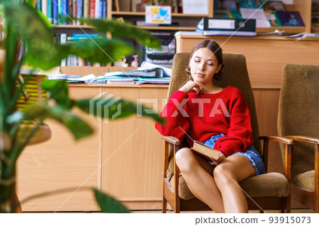 Cheerful brunette young woman laughing at funny story from book, happy Cheerful brunette young woman laughing at funny story from book, happy 93915073