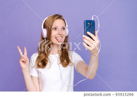 Woman dancing to music while listening to MP3 player with wired headphones. Woman dancing to music while listening to MP3 player with wired headphones. 93915266