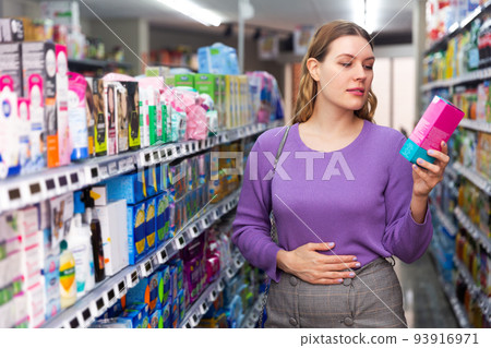 Woman choosing hygiene pads at supermarket 93916971