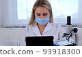 female research chemist scientist in a protective mask and gloves, dressed in a medical suit, with a 93918300