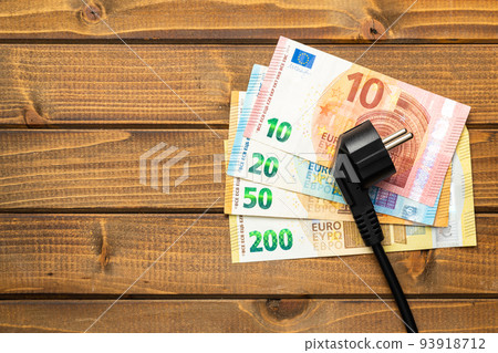 Electric plug and euro money on wooden table. Concept of increasing electric prices. 93918712