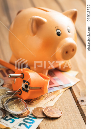 Electric plug, euro money and piggy bank on the wooden table. Concept of increasing electric prices. 93918722
