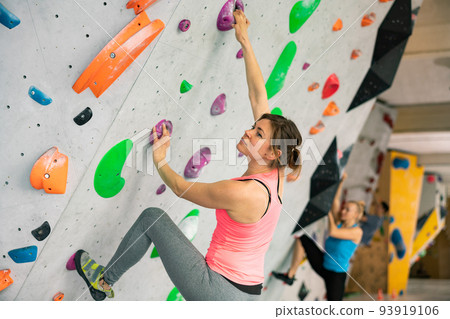 Woman grabbing ledges of artificial climbing wall Woman grabbing ledges of artificial climbing wall 93919106