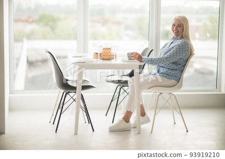Blonde mid aged woman having her morning coffee 93919210