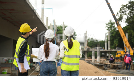 Rear view of architects and executive supervisor discussing project details at construction site. Industry, Engineer, construction concept Rear view of architects and executive supervisor discussing project details at construction site. Industry, Engineer, construction concept 93919914