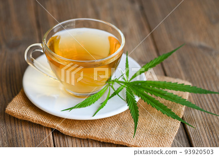 Cannabis tea herbal on tea cup with cannabis leaf marijuana leaves herb on wooden background, health tea with hemp leaf plant THC CBD herbs food and medical Cannabis tea herbal on tea cup with cannabis leaf marijuana leaves herb on wooden background, health tea with hemp leaf plant THC CBD herbs food and medical 93920503
