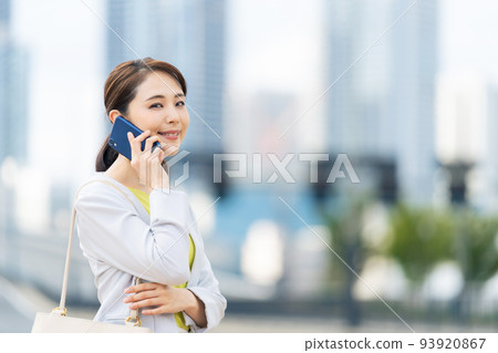 A woman talking on a smartphone with the city in the background 93920867