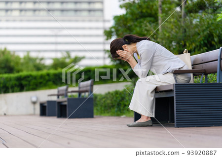 Depressed woman sitting on a park bench Depressed woman sitting on a park bench 93920887