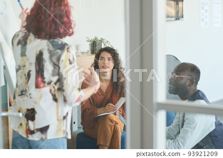 Young businesswoman with notepad looking at coach and listening to her Young businesswoman with notepad looking at coach and listening to her 93921209