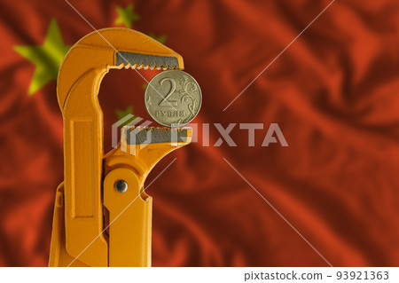 Russian two rubles coin held in an orange plumber wrench on the background of the flag of China. Reverse side of the coin. Russian two rubles coin held in an orange plumber wrench on the background of the flag of China. Reverse side of the coin. 93921363