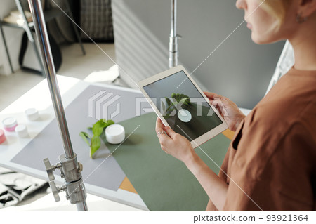 Hands of young assistant of photographer holding tablet over composition 93921364