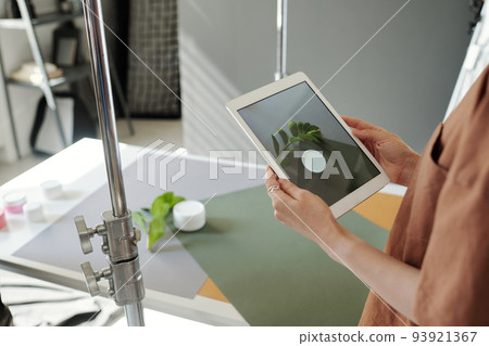 Close-up of young female assistant holding tablet over table with objects Close-up of young female assistant holding tablet over table with objects 93921367