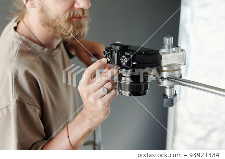 Hand of young modern cameraman adjusting settings of steadicam 93921384