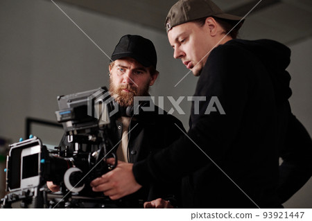Two serious men in black sweatshirta discussing settings of steadicam 93921447