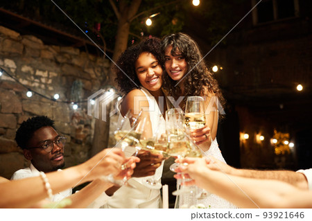 Happy young affectionate brides in wedding attire cheering up with friends Happy young affectionate brides in wedding attire cheering up with friends 93921646