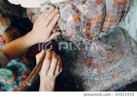 Man mosaics master in hat making smalt glass mosaic panel. 93922459