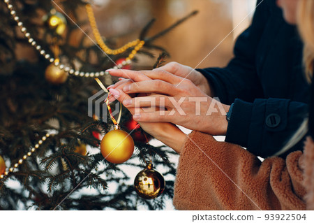 Young adult couple decorates christmas tree in winter forest. New year pine holiday party celebration concept 93922504
