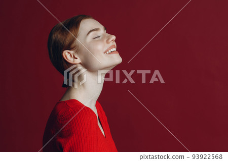 Portrait of young smile ginger woman profile portrait on red background. 93922568