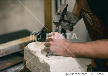 Man sculptor creates sculpt bust gypsum human woman sculpture with hammer. Statue craft creation workshop. Man sculptor creates sculpt bust gypsum human woman sculpture with hammer. Statue craft creation workshop. 93922583