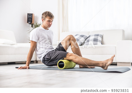 Young man massage thigh muscle with foam roller 93923831