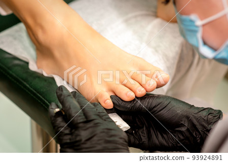 The podiatry doctor examines the toenails on the female foot The podiatry doctor examines the toenails on the female foot 93924891