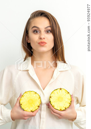 Young Caucasian smiling woman holding slices pineapple over white background, breast health concept 93924977