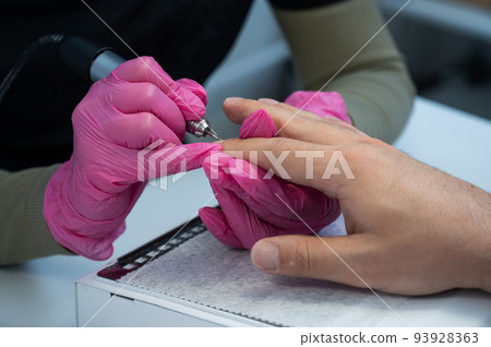 The master makes a hardware manicure to a male client. The master makes a hardware manicure to a male client. 93928363