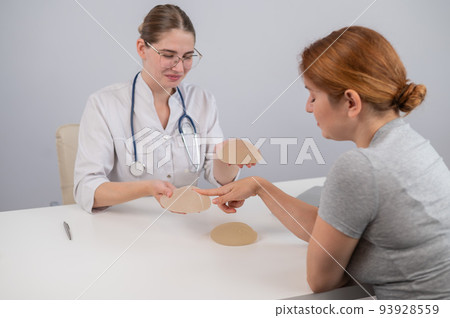 Caucasian woman and plastic surgeon choosing breast implants. Caucasian woman and plastic surgeon choosing breast implants. 93928559