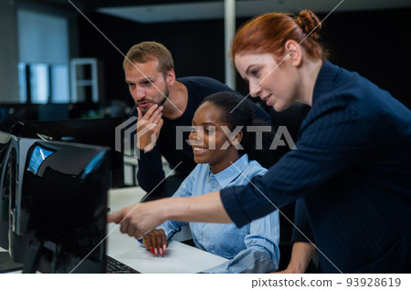 Colleagues discuss work. African young woman, caucasian and red-haired caucasian communicate in the office.  93928619