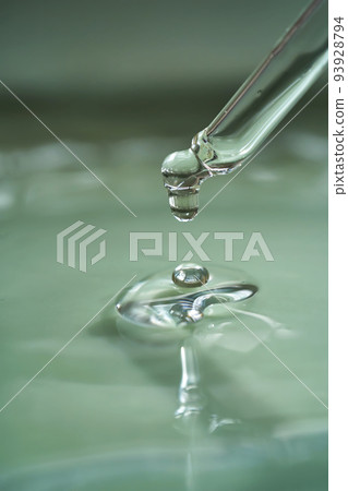 Dropper with serum or cosmetic oil on a green background. 93928794