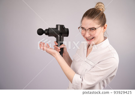 The masseur doctor holds a masseur gun on a white background. The masseur doctor holds a masseur gun on a white background. 93929425