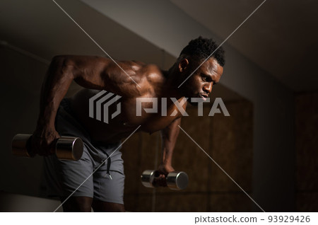 Attractive african american man doing arm exercises with dumbbells. Attractive african american man doing arm exercises with dumbbells. 93929426