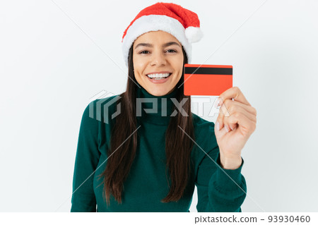 Portrait of cheerful young woman wearing santa hat Portrait of cheerful young woman wearing santa hat 93930460