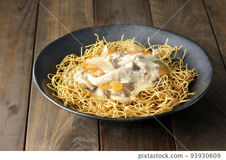A hot dish of udon noodles topped with bean paste containing shimeji mushrooms, carrots, and onions. 93930609