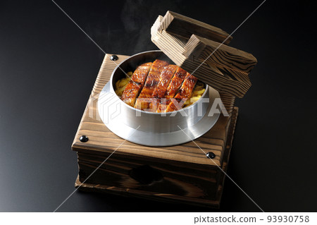Hot kamameshi with grilled eel on a black background Hot kamameshi with grilled eel on a black background 93930758