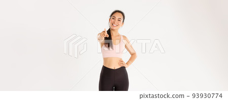 Sport, wellbeing and active lifestyle concept. Portrait of cheerful and enthusastic asian female fitness intrusctor, gym member in activewear inviting for training, pointing at camera and smiling 93930774