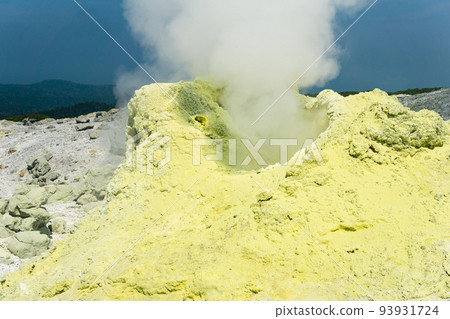 cone of sulfur deposits around a fumarole in a solfataric field illuminated by the sun against a stormy landscape in the distance cone of sulfur deposits around a fumarole in a solfataric field illuminated by the sun against a stormy landscape in the distance 93931724