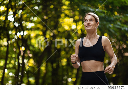 Happy athletic woman jogging by public park, copy space 93932671