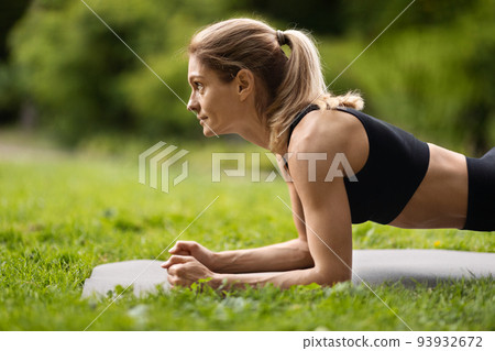 Side view of motivated sporty woman planking at public park 93932672