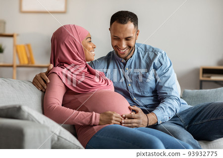 Portrait Of Happy Islamic Couple Expecting Baby Relaxing Together At Home Portrait Of Happy Islamic Couple Expecting Baby Relaxing Together At Home 93932775