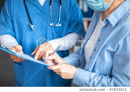 Smiling adult man doctor and european elderly lady patient signing documents in clinic office interior, cropped Smiling adult man doctor and european elderly lady patient signing documents in clinic office interior, cropped 93933012