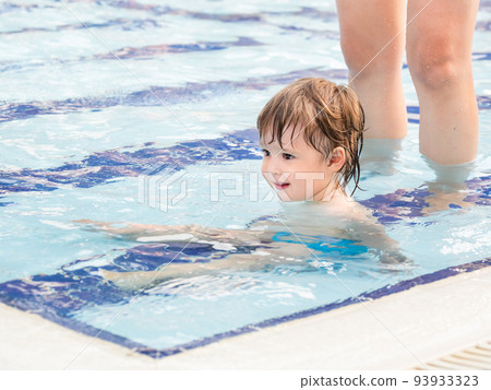 Toddler floats in paddling pool. Teaching children to swim from early childhood. Sport, active lifestyle and physical development. 93933323