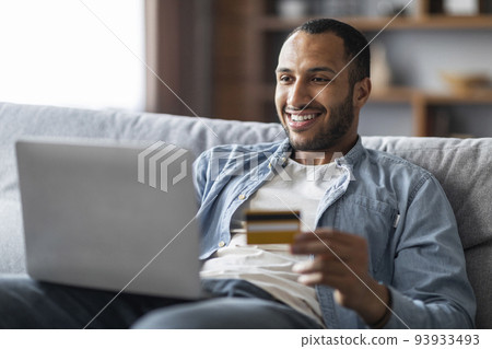 Online Shopping. Cheerful Handsome Black Man Using Laptop And Credit Card 93933493