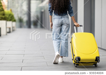 Unrecognizable young woman having journey abroad, carrying suitcase Unrecognizable young woman having journey abroad, carrying suitcase 93934004