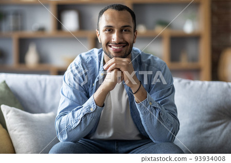 Portrait Of Happy Handsome Black Male Sitting On Couch In Home Interior Portrait Of Happy Handsome Black Male Sitting On Couch In Home Interior 93934008
